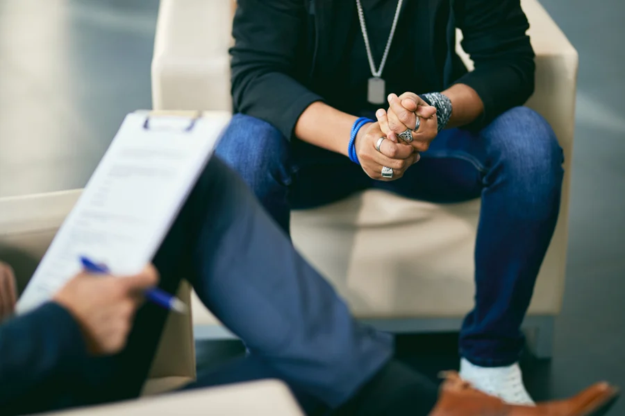 man wringing his hands while discussing alcohol withdrawal symptoms to a therapist