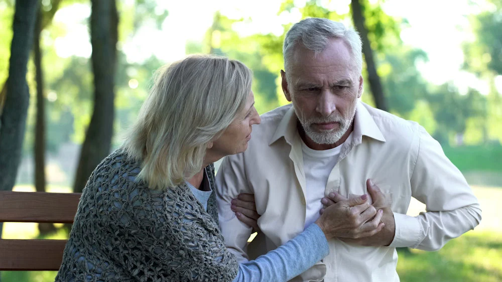 Woman supporting an older man with chest pain linked to heart damage from drugs